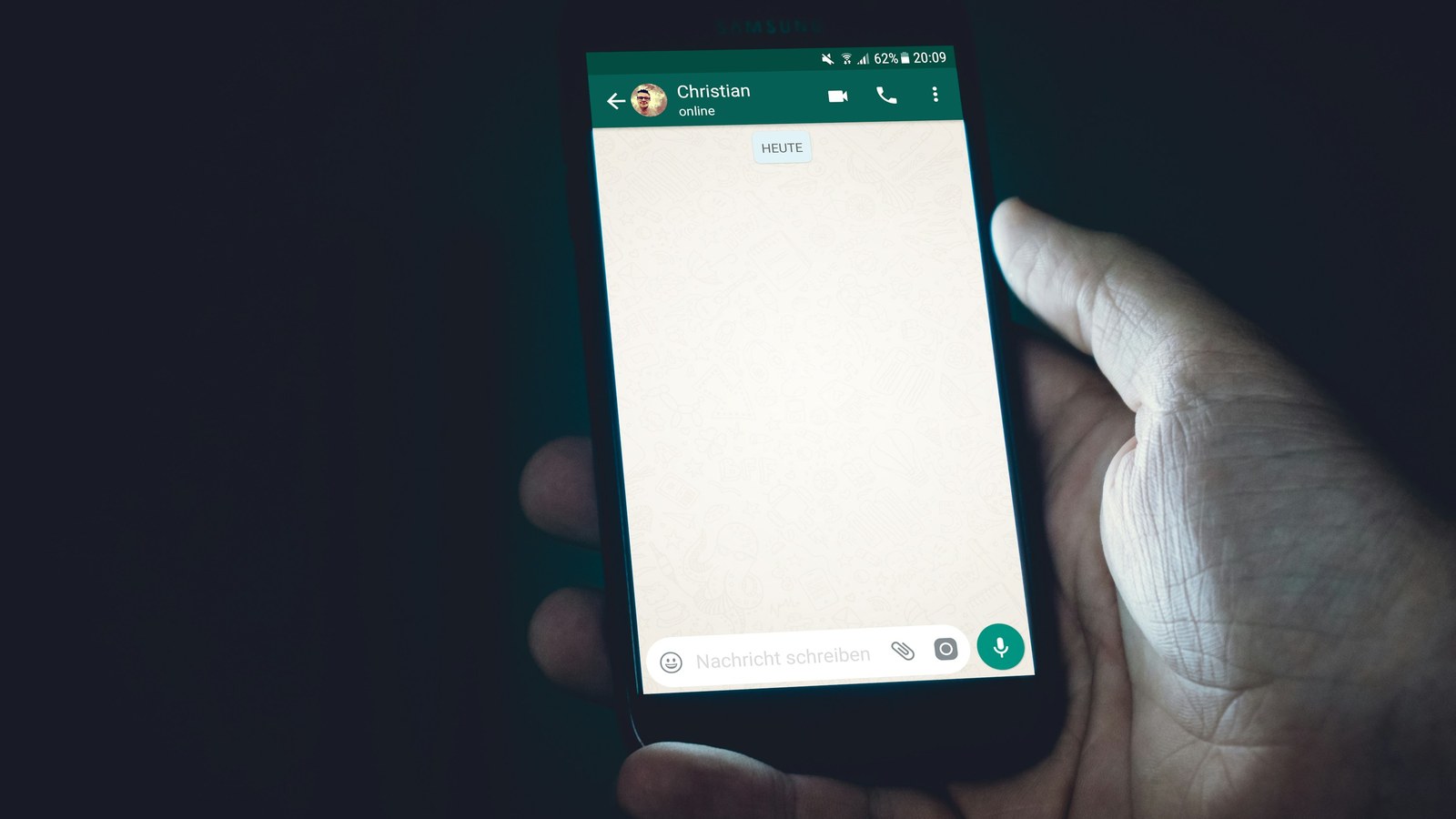 Una mano tiene uno smartphone con una chat aperta sullo schermo